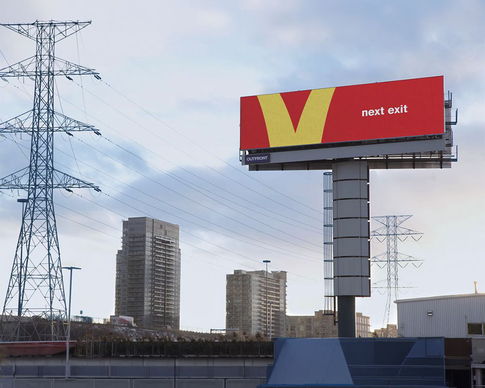 anuncio-mcdonalds-follow-the-arches-2018 Valla publicitaria roja de McDonald's con un recorte extremo de la curva amarilla de su logotipo sirviendo como flecha para indicar la dirección.