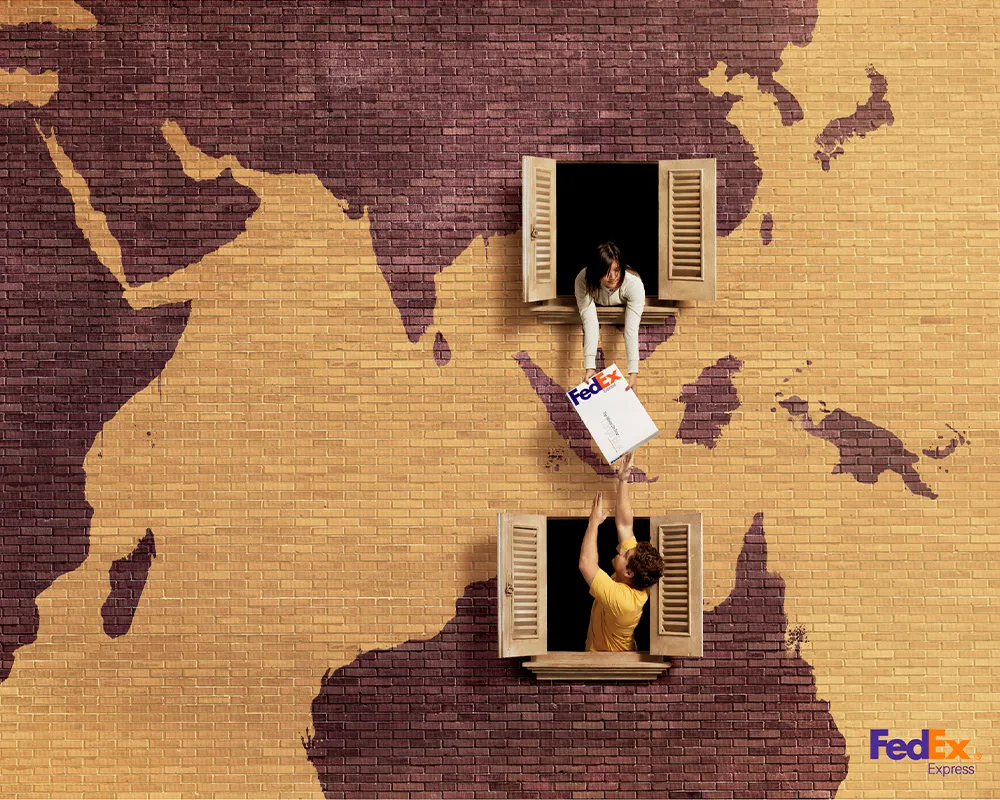 anuncio-fedex-neighbors-ddb-brasil-2010 Dos personas entregándose un paquete de FedEx de mano a mano a través de las ventanas de dos edificios contiguos que representan mapas continentales.